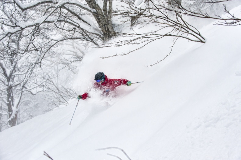 A skier in red descends a mountain at Myoko Kogen ski resort in Japan