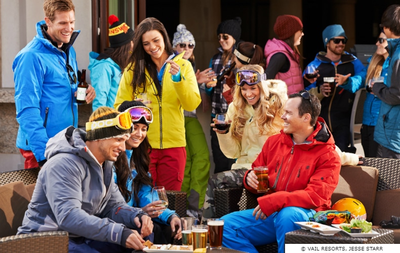 3 young couple in brightly colored ski gear enjoying some Apres Ski food & drinks