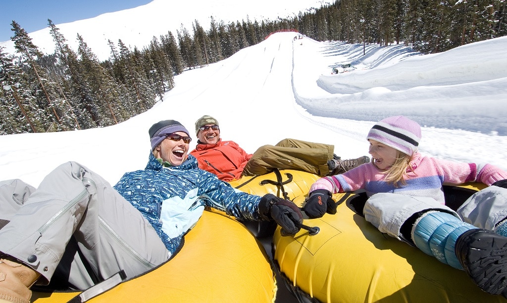 Close up on a family of three on a snow tubing run